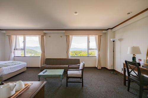 a hotel room with a bed and a couch and windows at Southern Cross Resort in Ito