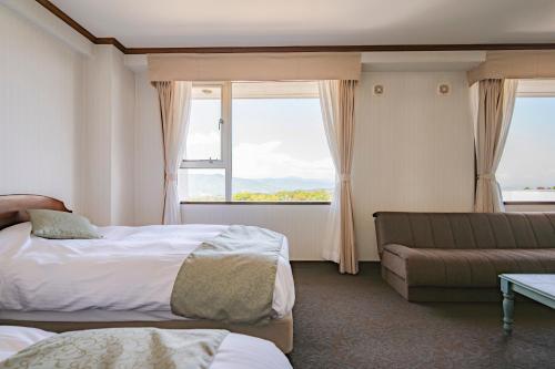 a hotel room with a bed and a couch at Southern Cross Resort in Ito