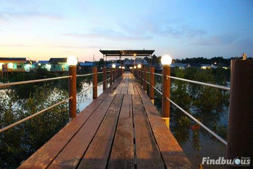 a wooden bridge over water with lights on it at Sea Lion Pulau Ketam Bungalow Homestay in Bagan Teochew