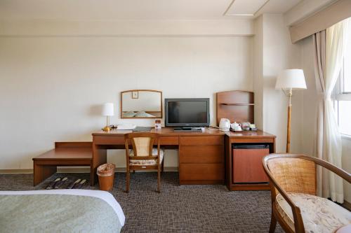 a hotel room with a desk with a computer and a mirror at Southern Cross Resort in Ito