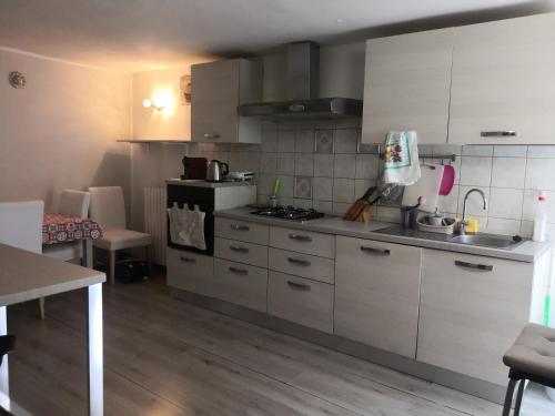 a kitchen with white cabinets and a stove top oven at Casa Vista Fiume in Susa