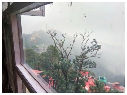 an open window with a view of a mountain at Hotel Amar Palace With mountain view in Shimla