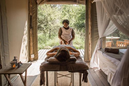a man and a woman laying on a bed in a room at Ngama Tented Safari Lodge in Guernsey Nature Reserve