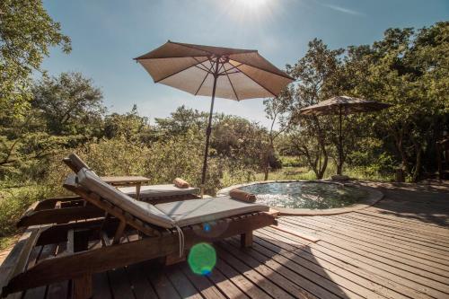 a wooden deck with a chair and an umbrella at Ngama Tented Safari Lodge in Guernsey Nature Reserve