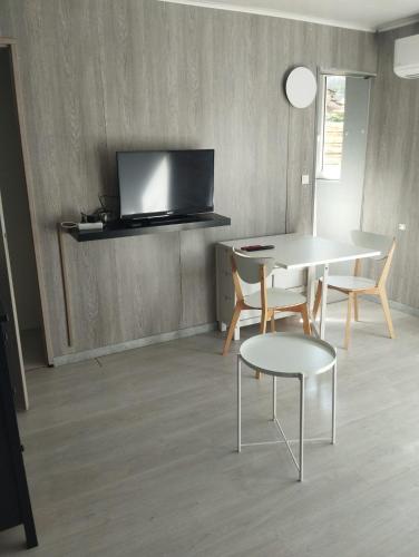 a living room with a table and chairs and a tv at F1 meublé indépendant in Chambray-lès-Tours