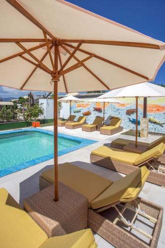 a pool with chairs and umbrellas next to a swimming pool at Pearl of Trawangan in Gili Trawangan