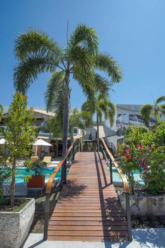 a wooden walkway leading to a pool with palm trees at Pearl of Trawangan in Gili Trawangan