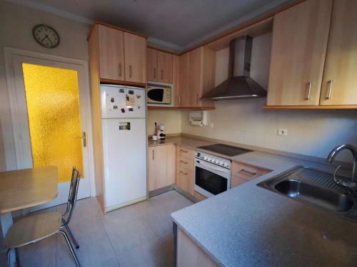 a kitchen with wooden cabinets and a white refrigerator at Cal Castro fantástica casa familiar in Sant Hilari Sacalm