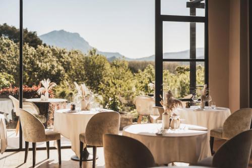 a restaurant with tables and chairs and a large window at Les Lodges Sainte-Victoire Hotel & Spa in Aix-en-Provence
