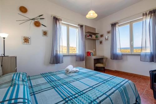 a bedroom with a bed with blue sheets and windows at Il Giglio Rosa in Sorso