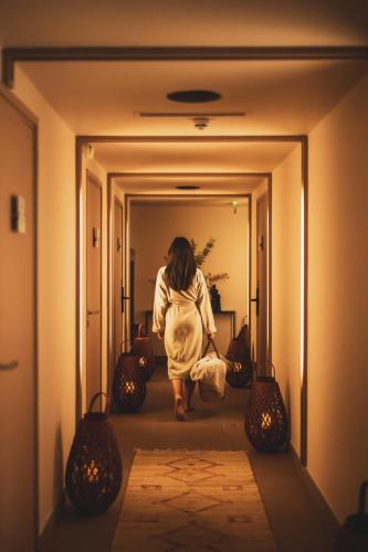 a woman walking down a hallway in a room at Les Lodges Sainte-Victoire Hotel & Spa in Aix-en-Provence