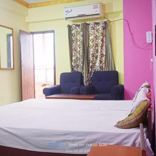 a bedroom with a bed and two chairs and a window at Hotel Shristy Residency in Dhanbād