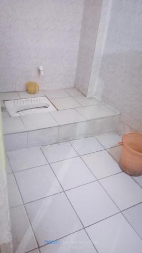 a white tiled bathroom with a sink and a toilet at Hotel Shristy Residency in Dhanbād