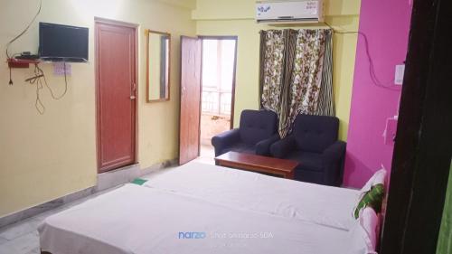 a room with a bed and two chairs and a tv at Hotel Shristy Residency in Dhanbād