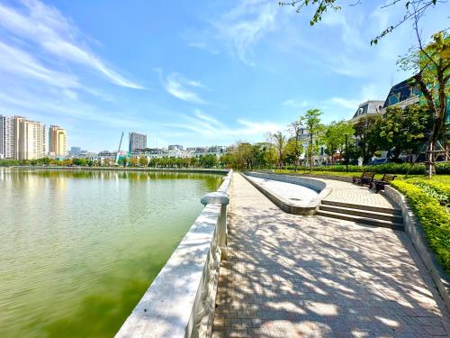 a park with a bench next to a body of water at 5 Star Apt Studio, Swimming Pool, Gyms, Quick To Airport in Hanoi