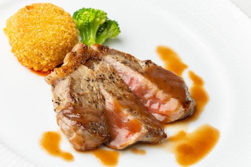 a plate of food with meat and broccoli on it at Southern Cross Resort in Ito
