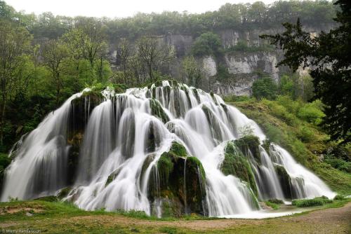 a large waterfall in the middle of a forest at Le chalet du lac d'étival in Étival