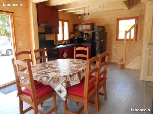 a dining room with a table and chairs and a kitchen at Le chalet du lac d'étival in Étival