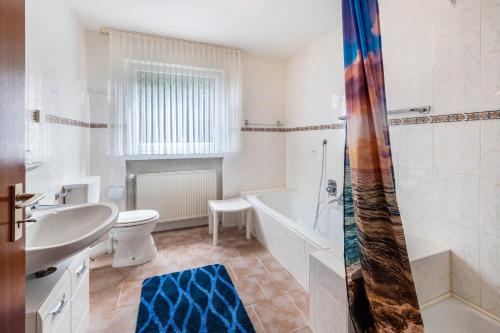 a bathroom with a tub and a toilet and a sink at Ferienwohnung Neuenrade in Neuenrade