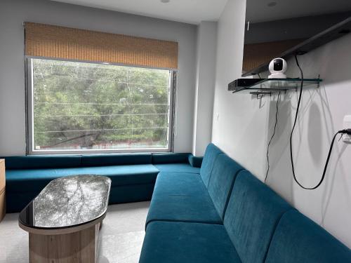 a living room with a blue couch and a window at Hotel Savaya Luxury Stay Near AIIMS Rishikesh in Rishīkesh