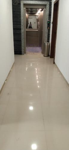 a hallway with a white tile floor in a building at Hotel Joy Executive in Pune