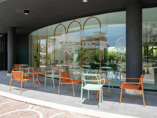 a group of chairs and tables in front of a building at B&B HOTEL Latina in Latina