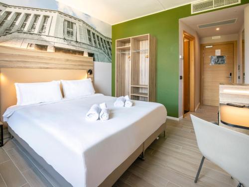 a bedroom with a large white bed and a desk at B&B HOTEL Latina in Latina