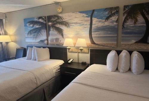 two beds in a hotel room with a painting on the wall at Days Inn by Wyndham Fort Lauderdale-Oakland Park Airport N in Fort Lauderdale