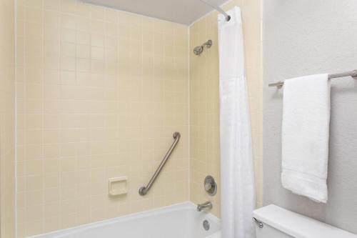 a bathroom with a tub and a shower with a towel at Days Inn by Wyndham Orlando Conv. Center/International Dr in Orlando