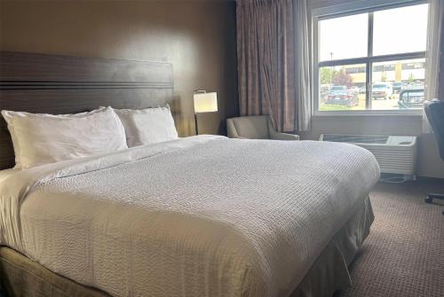 a hotel room with a large bed and a window at Ramada by Wyndham Sherwood Park in Sherwood Park