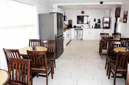 a kitchen and dining room with tables and a refrigerator at Ramada by Wyndham Sherwood Park in Sherwood Park