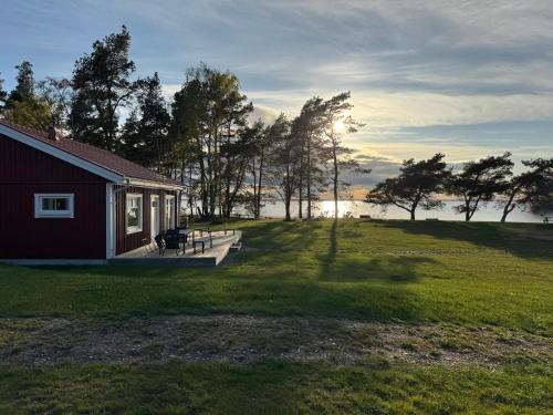 a small red house with a porch and a field at Stora Frögården in Mörbylånga