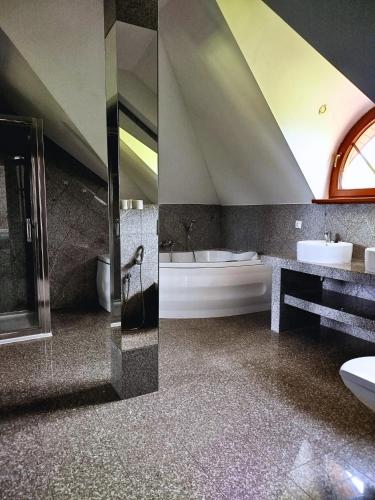 a bathroom with a tub and a toilet and a sink at Rezydencja Gołębiówka Mazury in Targowo