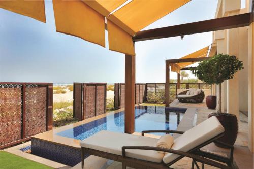 a pool with two chairs and a table next to a house at Park Hyatt Abu Dhabi Hotel and Villas in Abu Dhabi