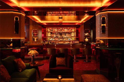 a bar with a couch and a chair in a room at Hôtel Martinez, in The Unbound Collection by Hyatt in Cannes