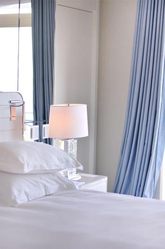 a bedroom with a bed with a lamp and blue curtains at Hôtel Martinez, in The Unbound Collection by Hyatt in Cannes
