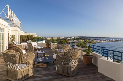 a balcony with chairs and tables and the water at Hôtel Martinez, in The Unbound Collection by Hyatt in Cannes