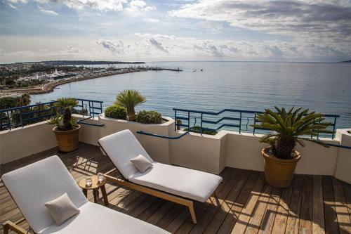 a balcony with two chairs and a view of the water at Hôtel Martinez, in The Unbound Collection by Hyatt in Cannes