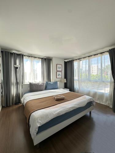 a bedroom with a large bed and two windows at Budget 2 bedrooms Apartment in Huahin in Hua Hin