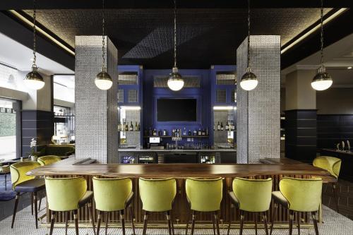 a bar with a wooden table and yellow chairs at Hyatt Place Knoxville/Downtown in Knoxville