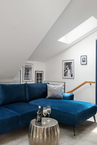 a blue couch in a living room with two glasses of wine at Coco Chanel Boutique Apartment by goodnite cz in Brno