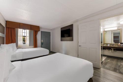 a white bedroom with two beds and a bathroom at Quality Inn & Suites Airport in Charlotte
