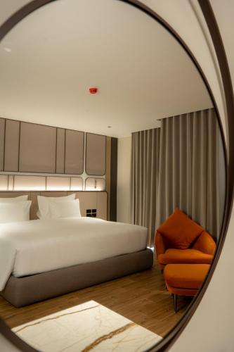 a bedroom with a bed and a chair in a mirror at Richmann Resort Hotel Hatyai in Hat Yai