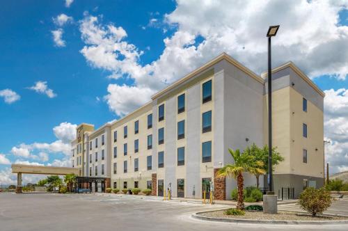 a large white building with a palm tree in a parking lot at Comfort Suites of Las Cruces I-25 North in Las Cruces