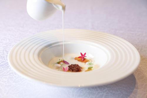 a white plate with a bowl of food with a spoon at Kempinski Hotel Fuzhou in Fuzhou
