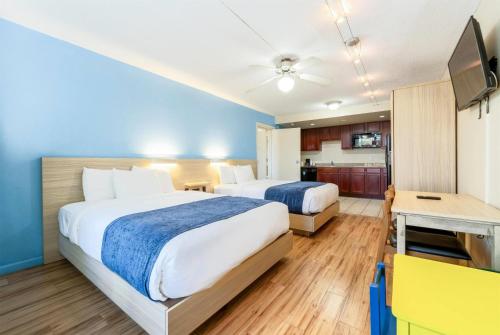a hotel room with two beds and a kitchen at Ramada by Wyndham Flamingo Water Park in Kissimmee