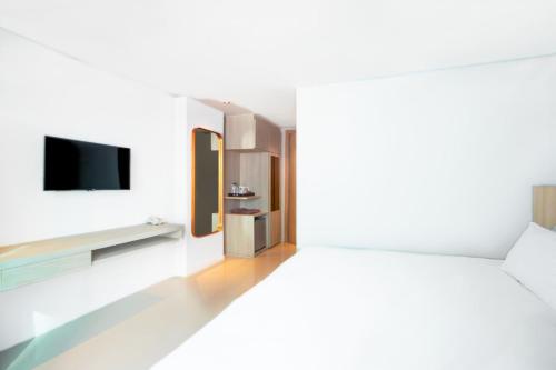 a bedroom with a bed and a tv on a wall at Zand Morada Pattaya in Jomtien Beach