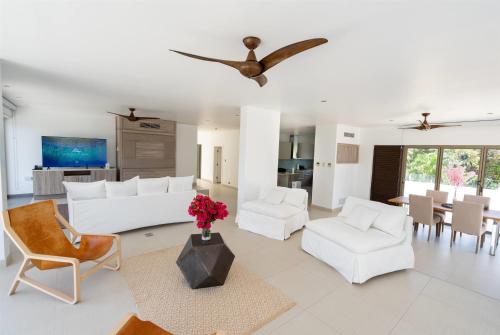 a living room with white furniture and a dining room at Hodges Bay Resort & Spa, an HQ Luxury Resort & Residences in Saint Johnʼs