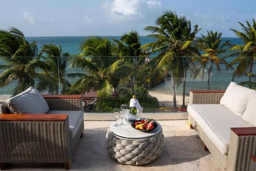 a patio with a table with a view of the ocean at Hodges Bay Resort & Spa, an HQ Luxury Resort & Residences in Saint Johnʼs