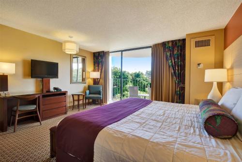 a hotel room with a bed and a desk and a television at Hilo Hawaiian Hotel, Trademark Collection by Wyndham in Hilo